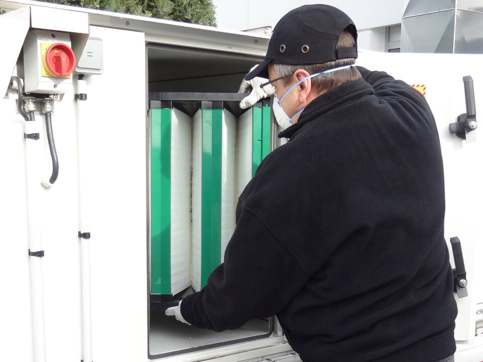 A technician replacing a filter inside a mobile laboratory unit.