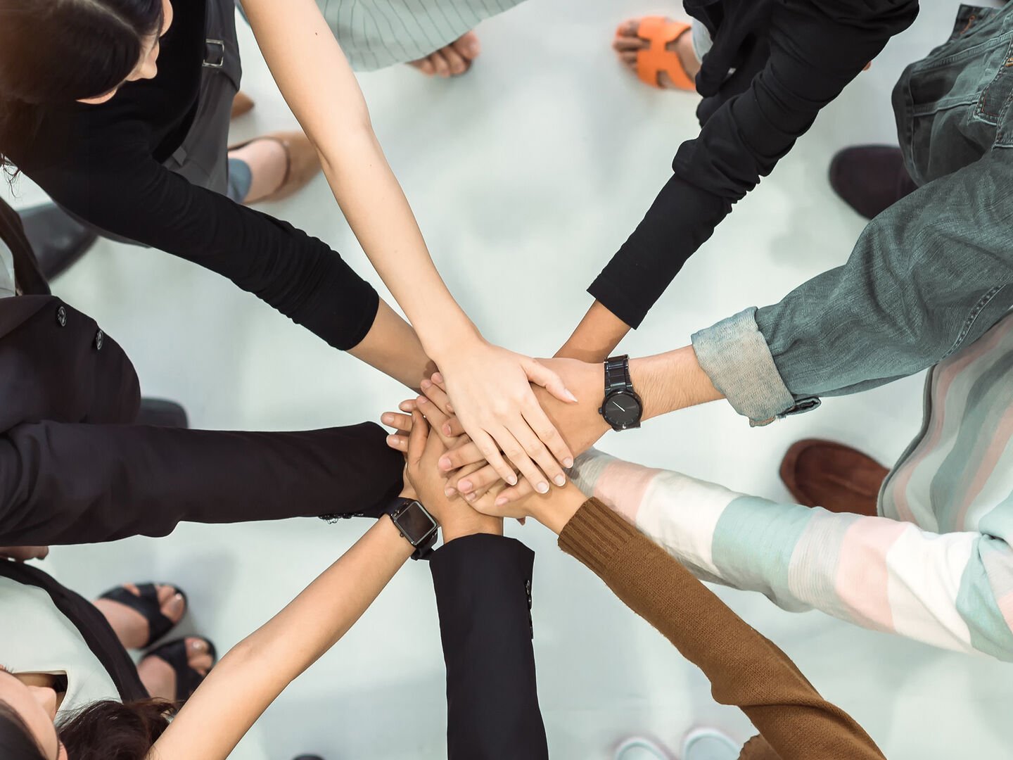 Overhead view of a group of people’s hands joined together, representing team unity.