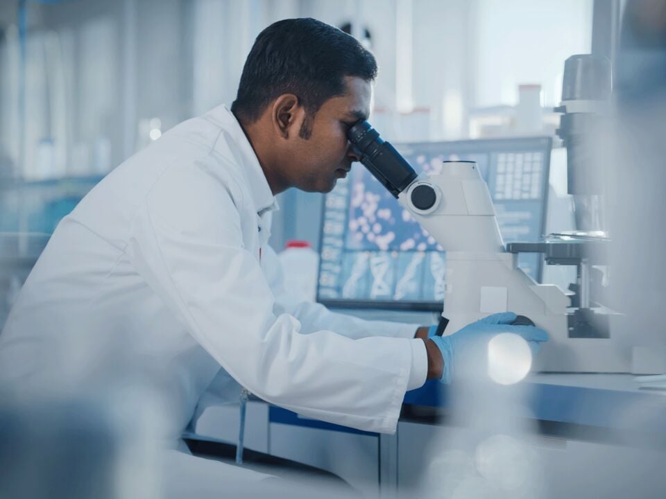 A scientist examining a sample under a microscope in a laboratory
