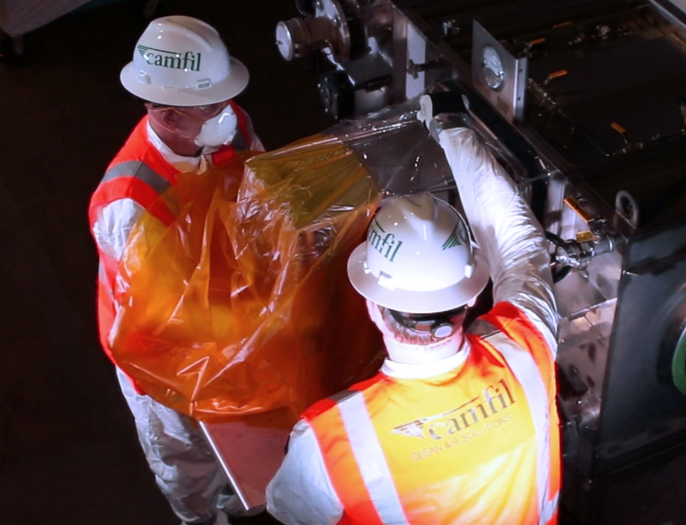 Two Camfil workers illustration a bag-in/bag-out process.