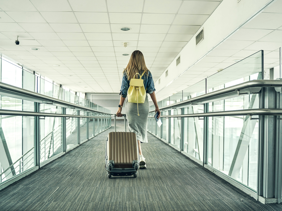 Woman walking down the hall of an airport with luggage