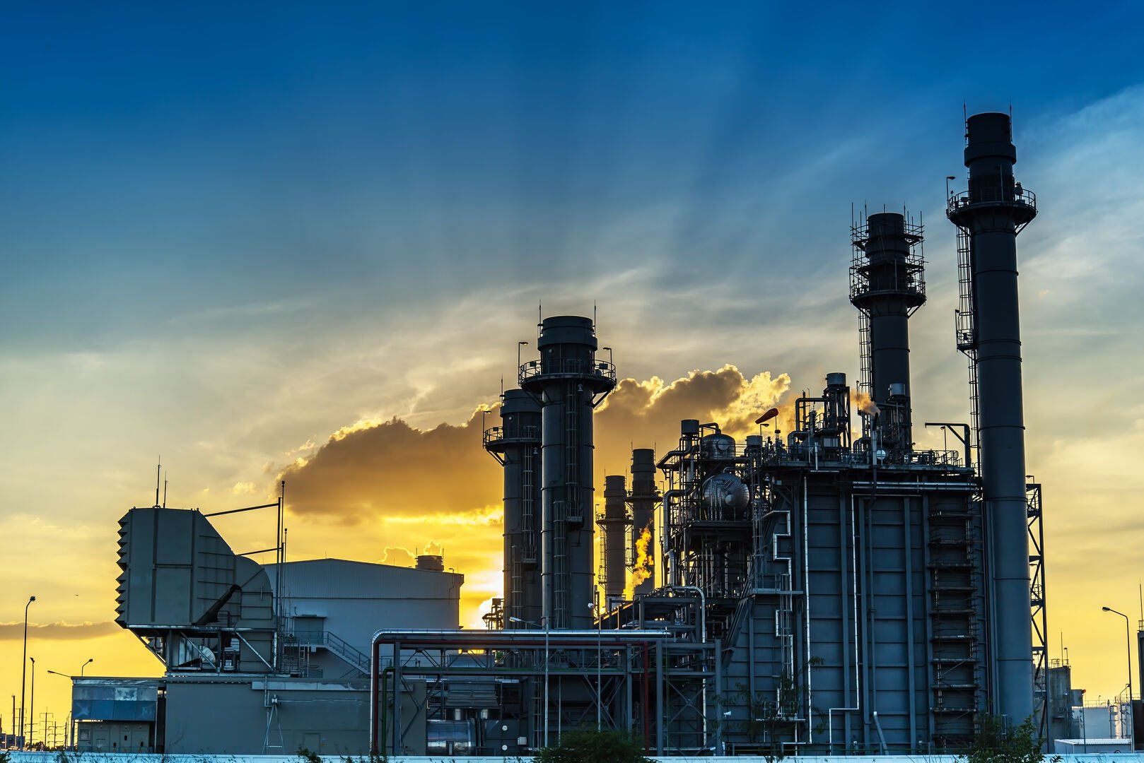Factory silhouette against an orange sunset sky.
