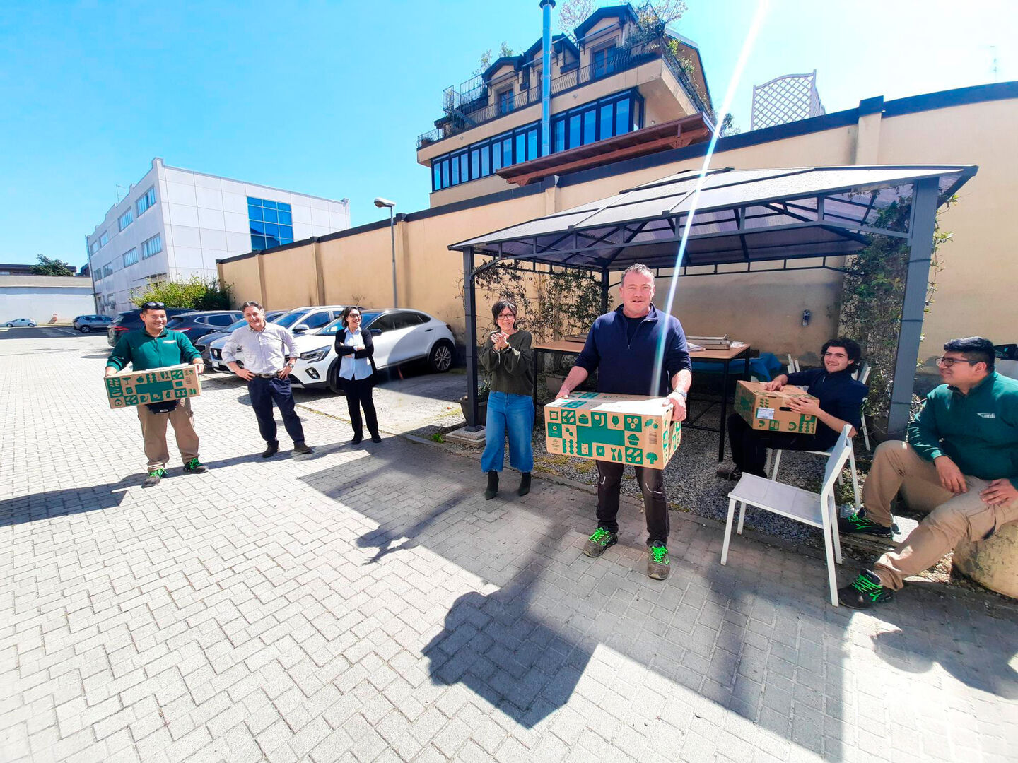Colleghi nel cortile esterno di Camfil Italia durante la premiazione del contest antispreco, mentre mostrano le box premio assegnate alle migliori idee
