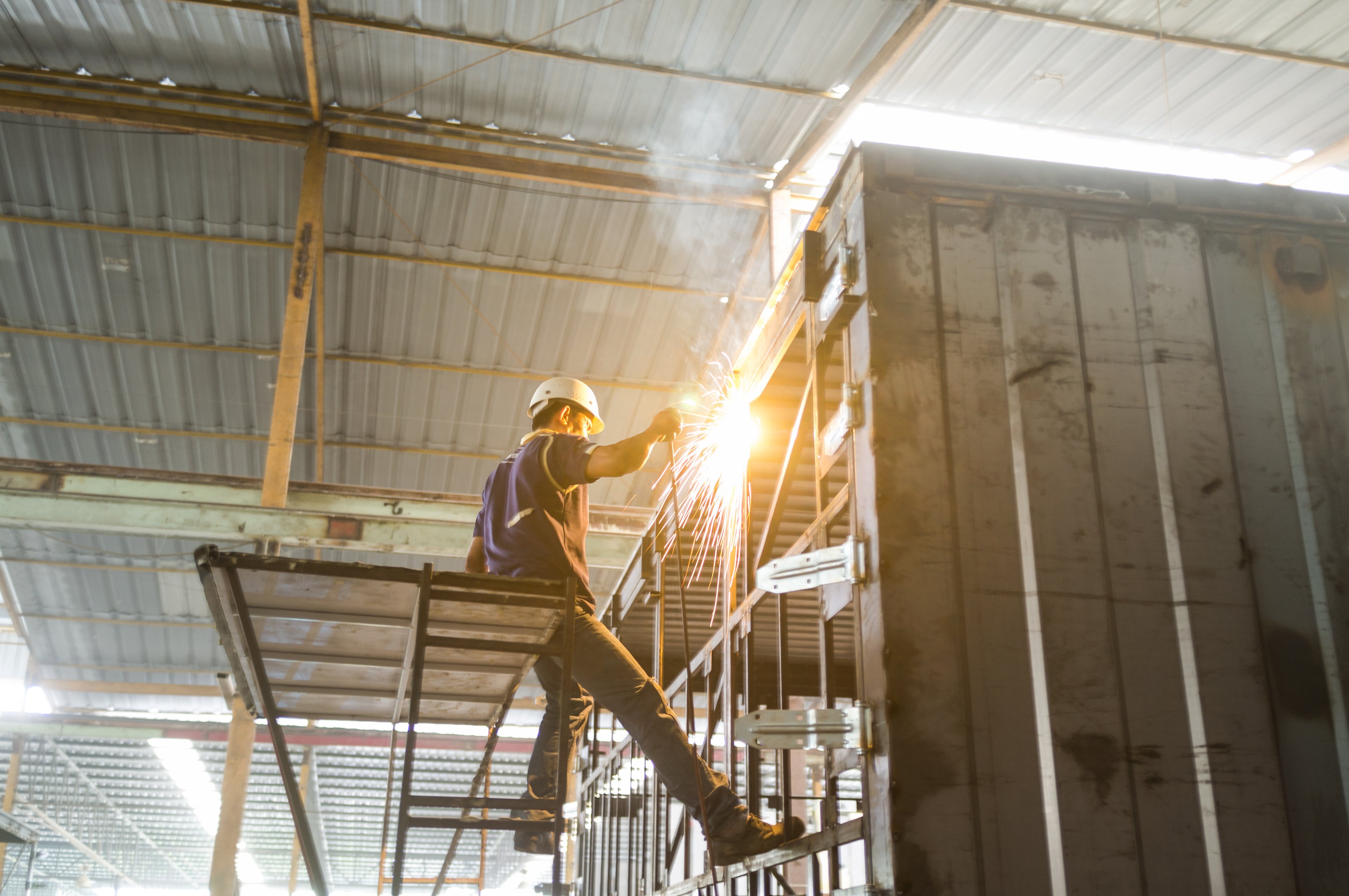 Industry worker with welding steel to build container structure.