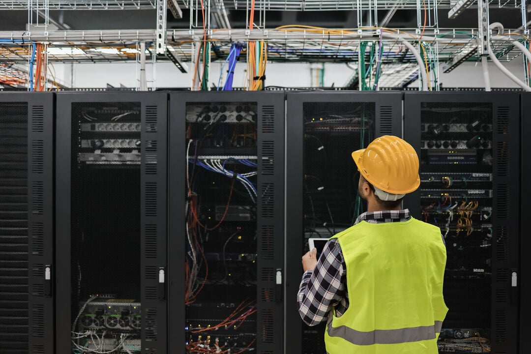 Person standing next to a server rack in a data center