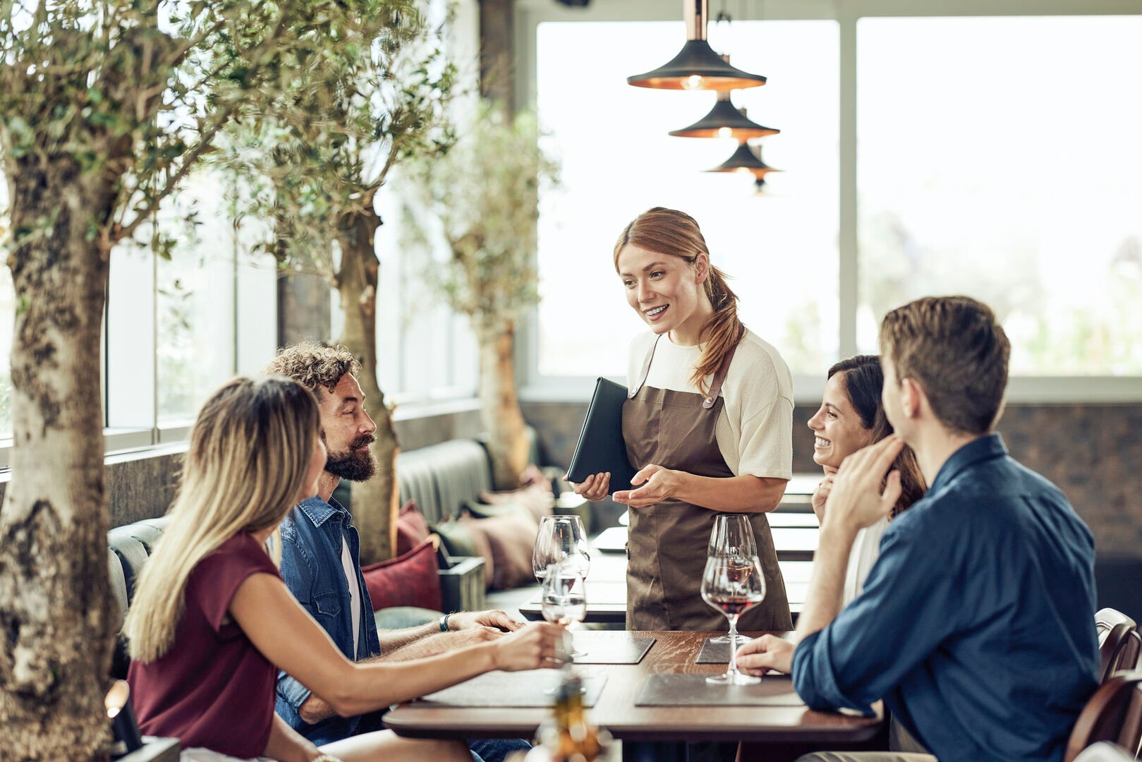 People sitting in a restaurant talking to a friendly waitress
