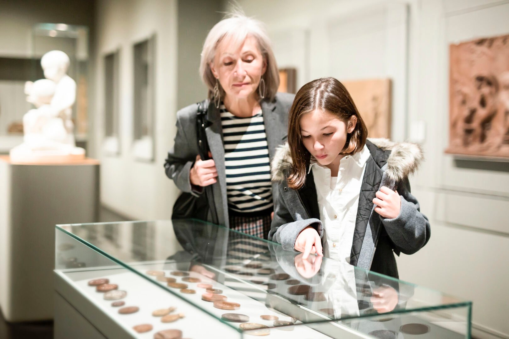 Woman and young girl looking at a coin collection in a museum
