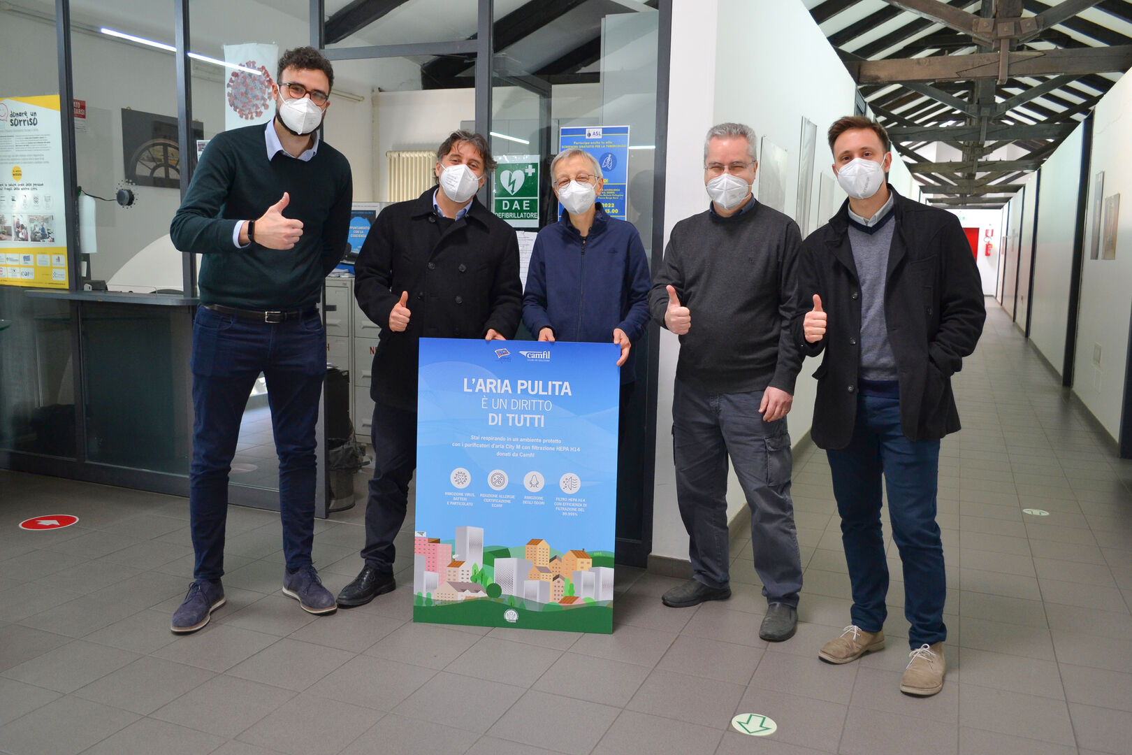 Gruppo di rappresentanti durante una visita al Sermig, posano con un poster dedicato al diritto all’aria pulita, a sostegno delle iniziative Camfil per ambienti più salubri