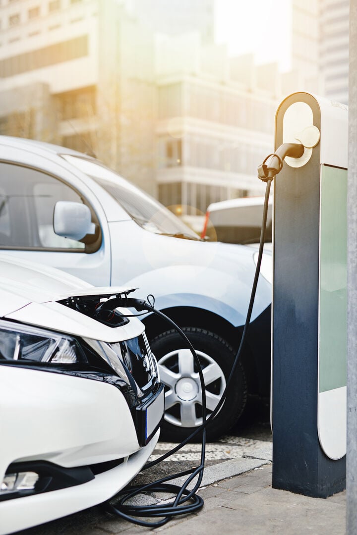 Electric car charging station. Close up of the power supply plugged into an electric car being charged. - Image