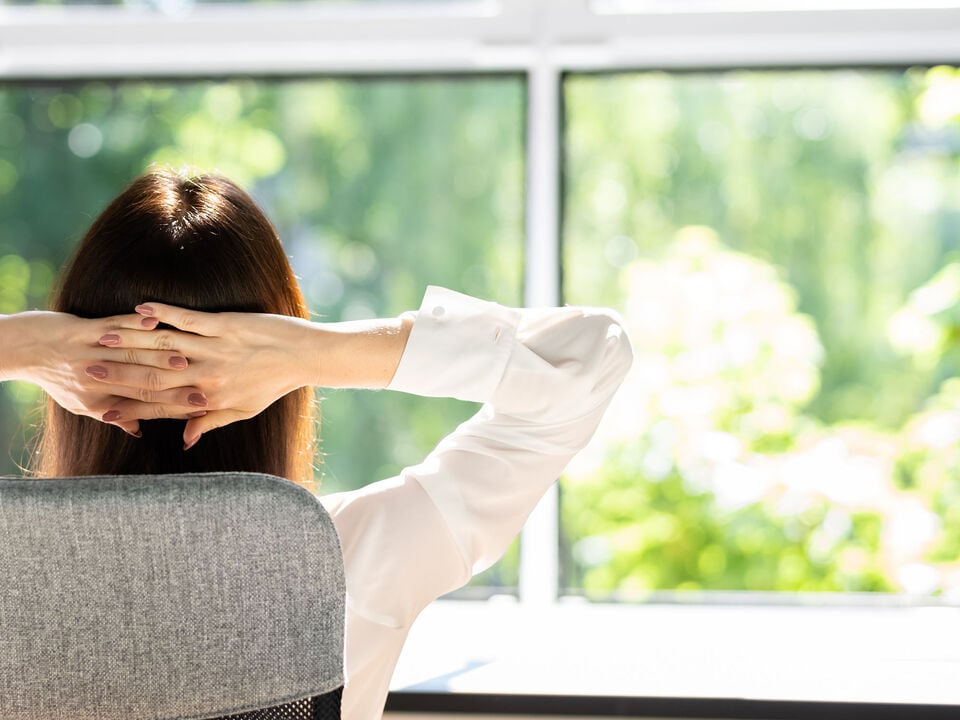 Woman sitting by a window, breathing fresh air.